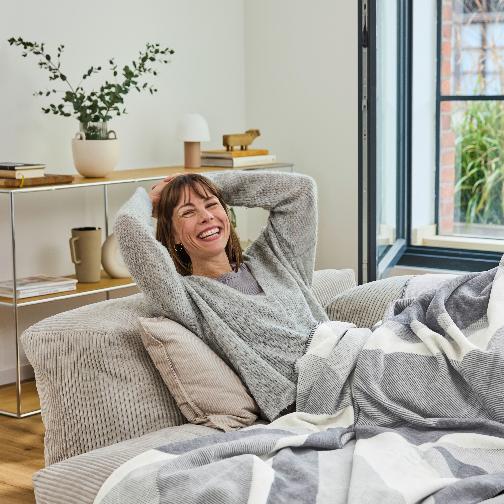 Frau, Sofa, Wohnzimmer, graue Strickjacke, Decke